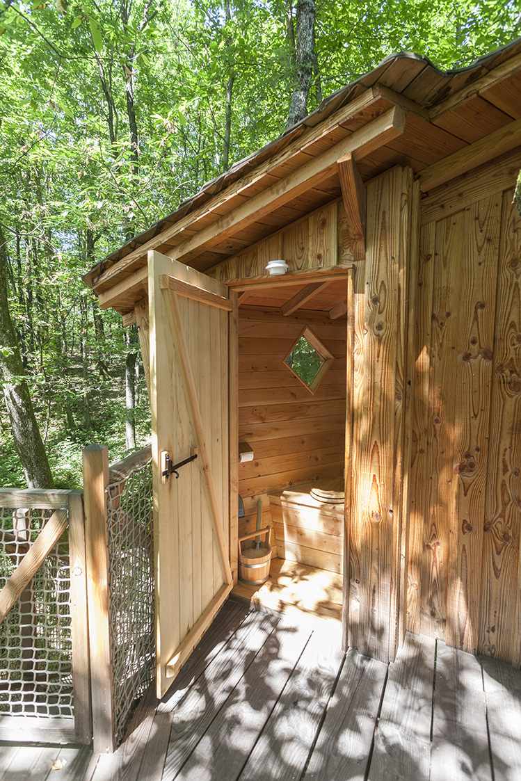 photojp-angei-jp-angei2496 Cabane en bois perchée, avec une entrée en bois et vue sur la forêt verdoyante.
