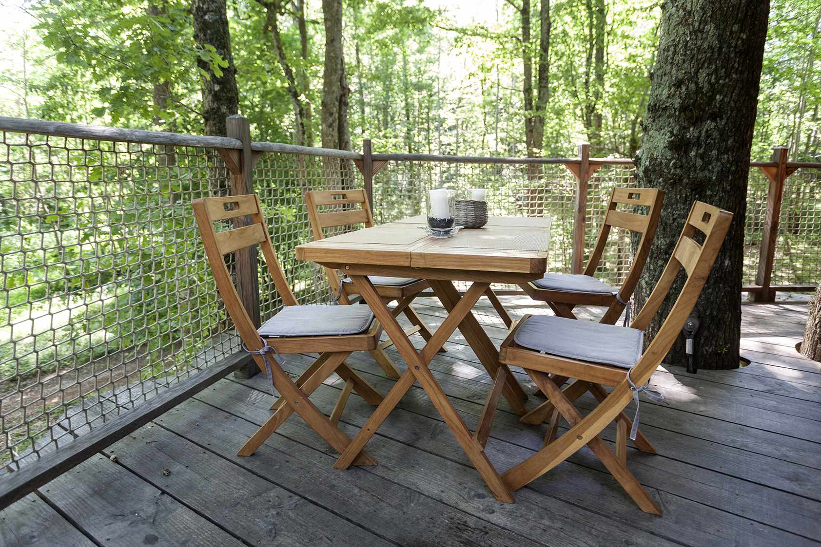 photojp-angei-jp-angei2550 Cabane perchée en bois avec table et chaises sur une terrasse entourée darbres.