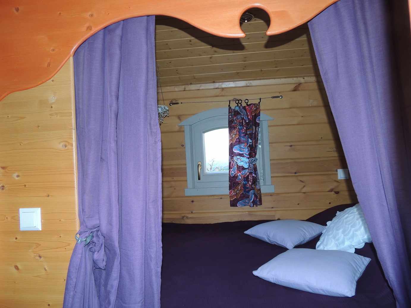 018b Cabane en bois à Limousin, avec un lit douillet et des rideaux violets.