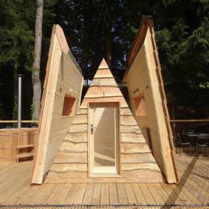 Cabane en bois en forme de tipi, entourée dune terrasse en bois et dun jacuzzi.