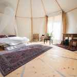 Tente glamping spacieuse avec lit douillet et décoration chaleureuse.