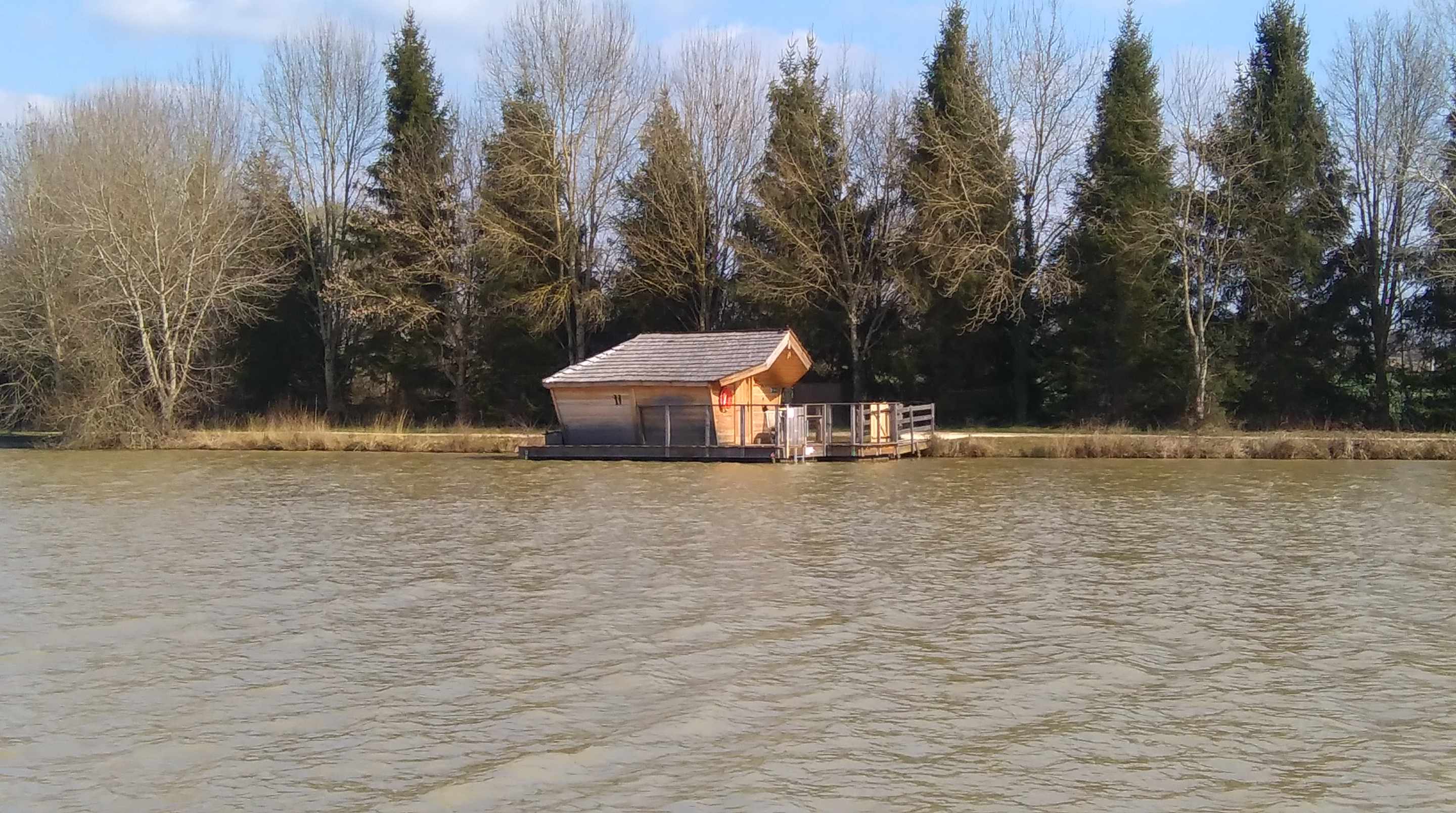 IMAG0574 Cabane flottante en bois sur leau, entourée darbres en Nouvelle-Aquitaine.