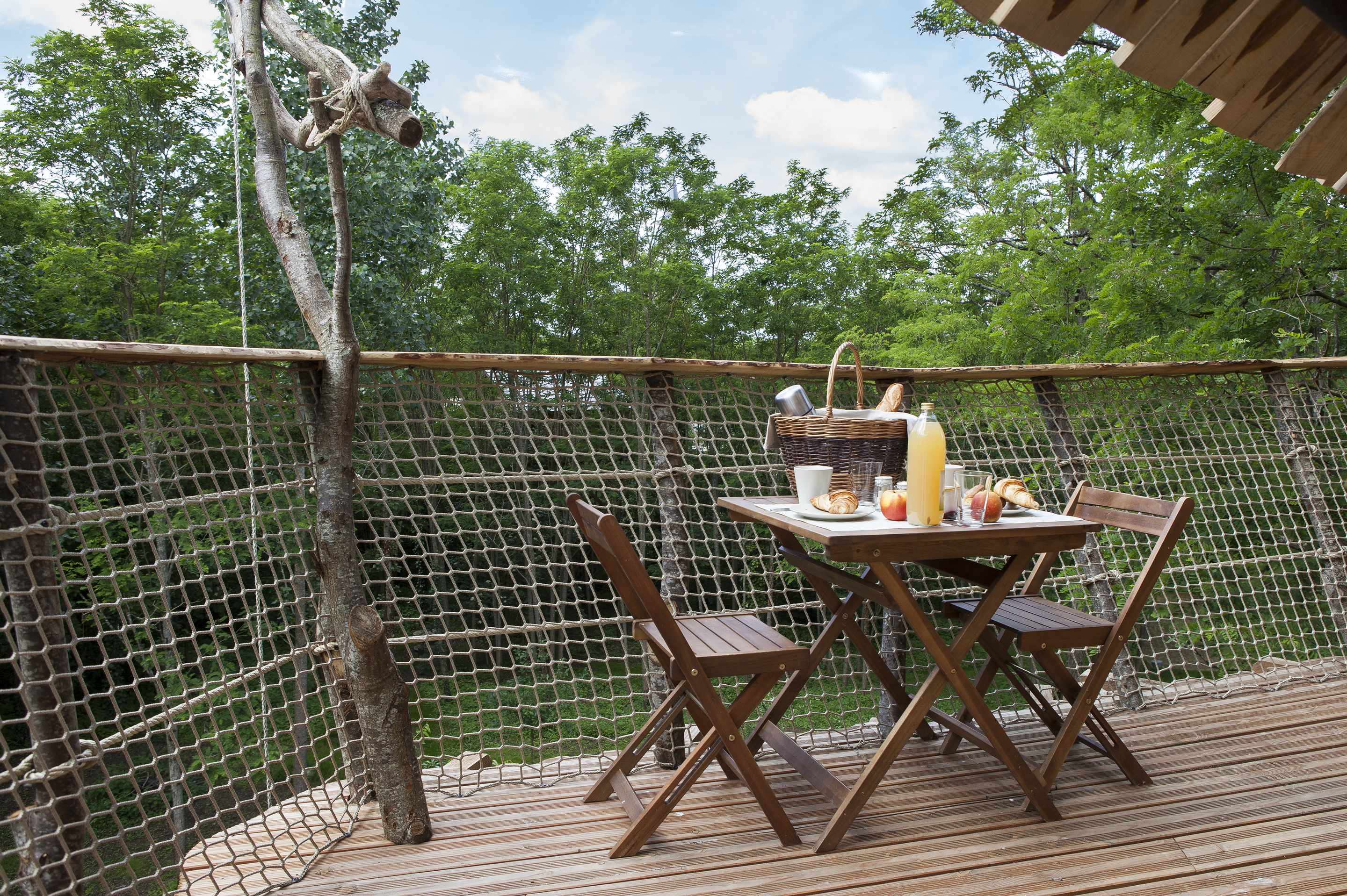 cab_ver_18 Cabane dans les arbres avec une terrasse en bois et un petit déjeuner en plein air.