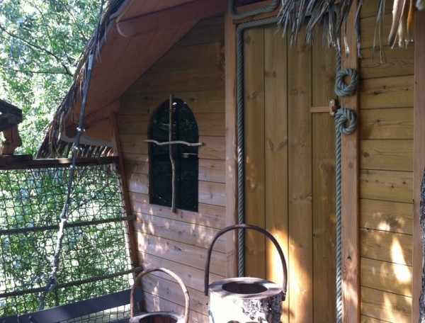 Cabane perchée en bois à lIle-de-France, avec des lanternes en tronc darbre.