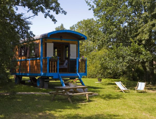 Charmante roulotte colorée avec terrasse, entourée dun jardin verdoyant.