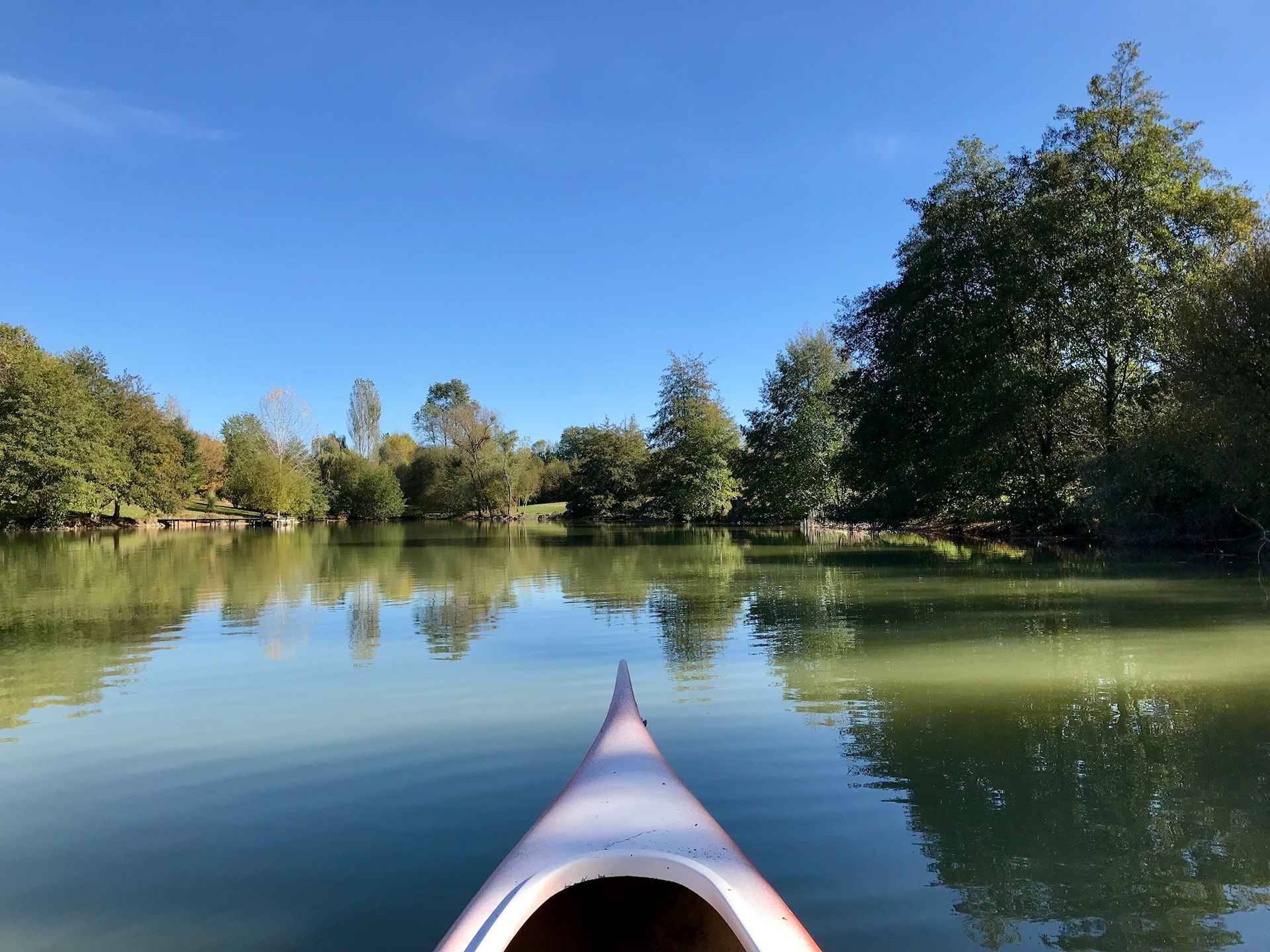 IMG_0216 Canoë sur un lac paisible, entouré darbres verdoyants en Aquitaine.
