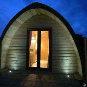 Cabane en bois avec une porte éclairée, ambiance nocturne apaisante.