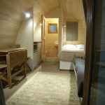 Chalet en bois chaleureux avec lit double et coin repas, ambiance cosy.