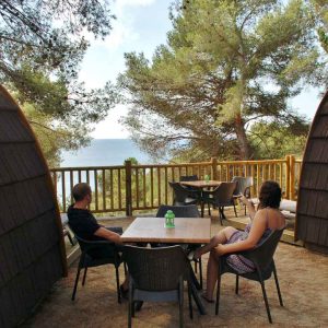 Hébergement en cabane avec vue sur la mer, entouré de pins et espace détente.