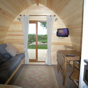 Intérieur dune cabane en bois, avec un canapé et une vue sur la nature.