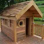 Charmante cabane en bois avec un toit en ardoise et une terrasse en bois.