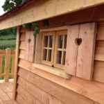 Cabane en bois avec fenêtres à cœurs et terrasse en bois. Ambiance chaleureuse et naturelle.