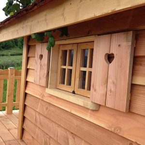 Cabane en bois avec fenêtres à cœurs et terrasse en bois. Ambiance chaleureuse et naturelle.
