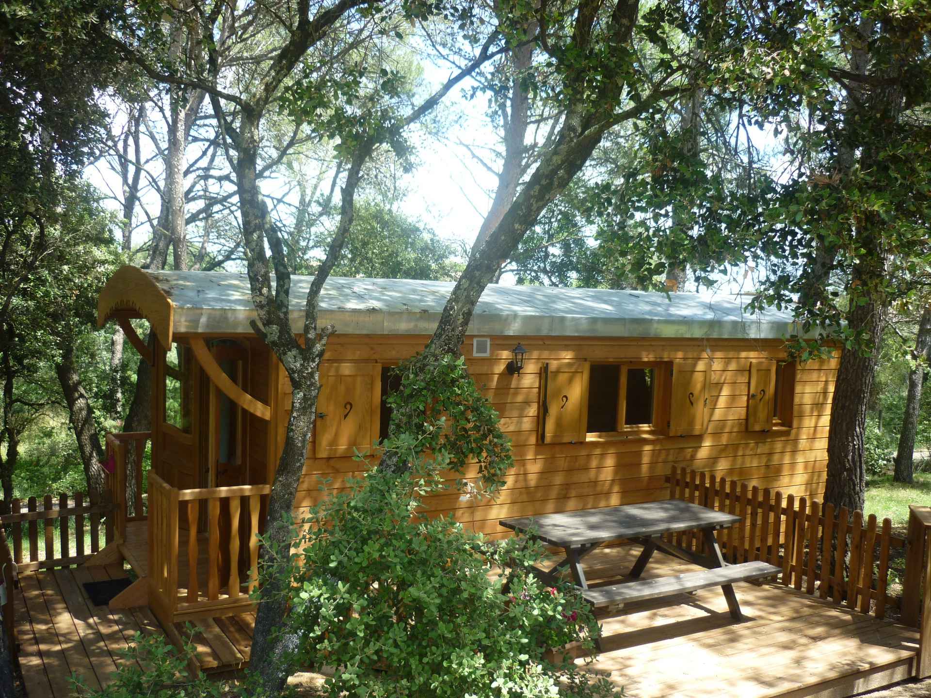 P1060317 Cabane en bois nichée dans la nature, avec terrasse et table en extérieur.