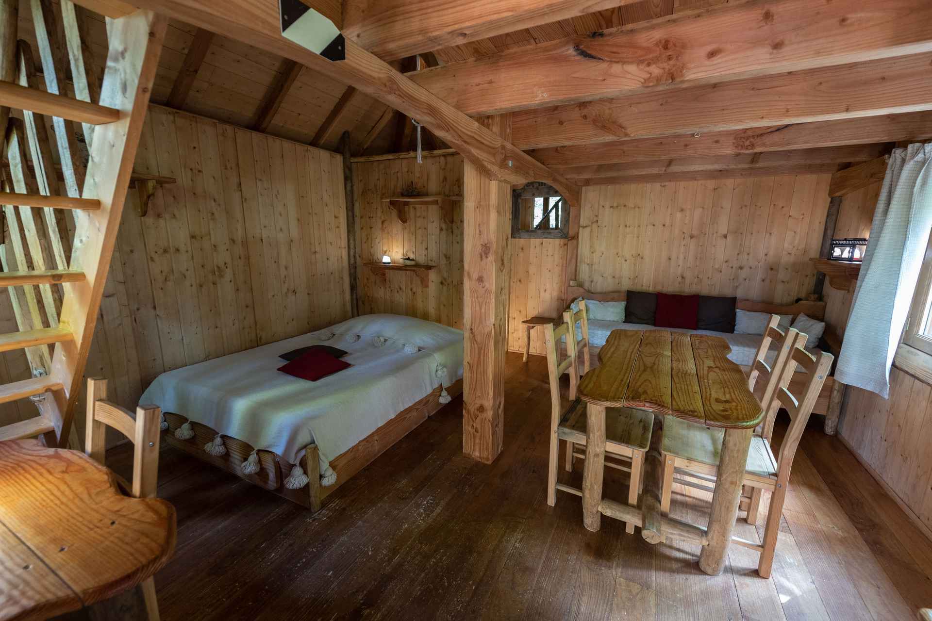 version-internet-20 panda Cabane en bois chaleureuse avec lit douillet et table en bois dans un cadre naturel.