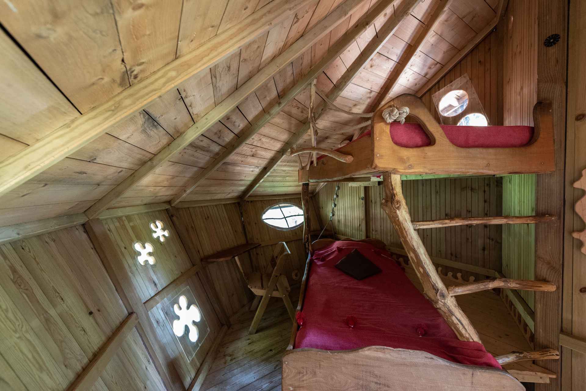 version-internet-42 castor Cabane en bois avec lits en alcôve et fenêtres rondes, ambiance chaleureuse et naturelle.