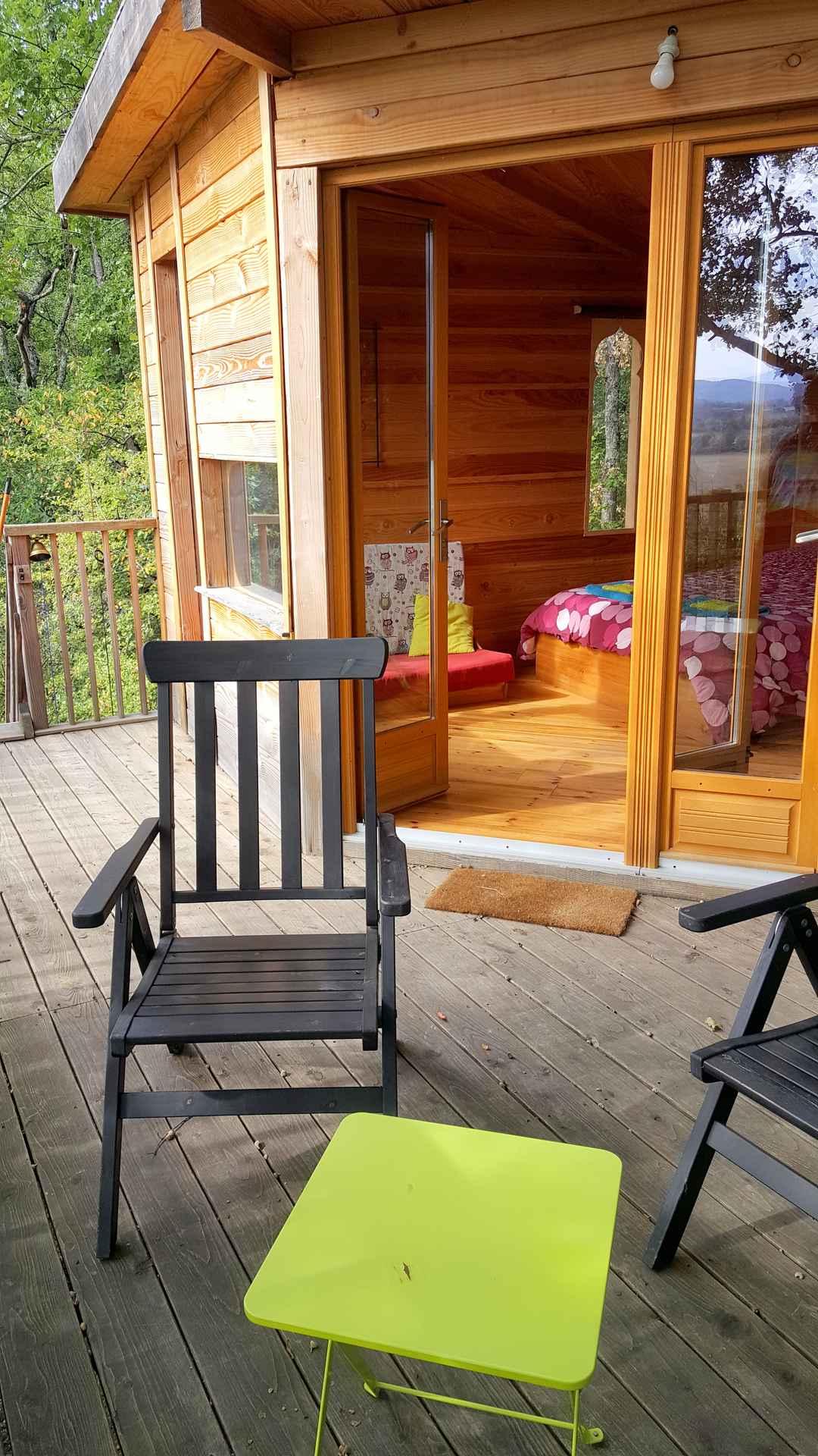 20181011_150641 Cabane en bois avec terrasse, fauteuils noirs et vue sur la nature environnante.