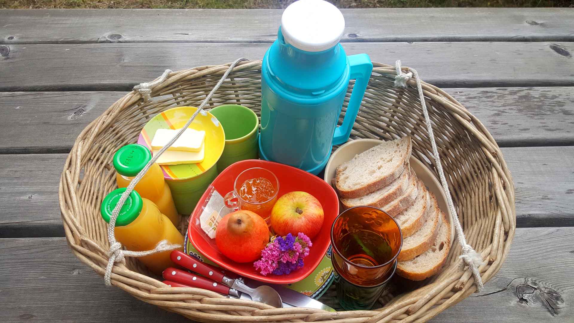 20181012_090226 Panier pique-nique coloré avec fruits, pain et boissons, parfait pour un hébergement insolite.