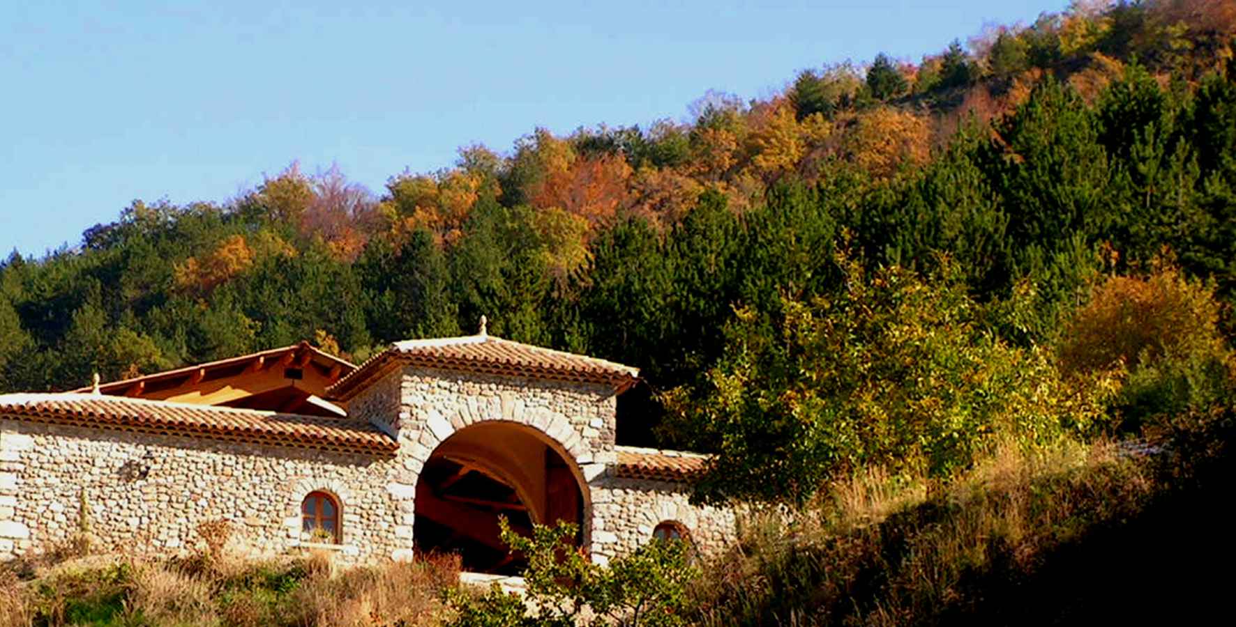 4 Hébergement insolite en pierre avec un arc, entouré de verdure en Auvergne-Rhône-Alpes.
