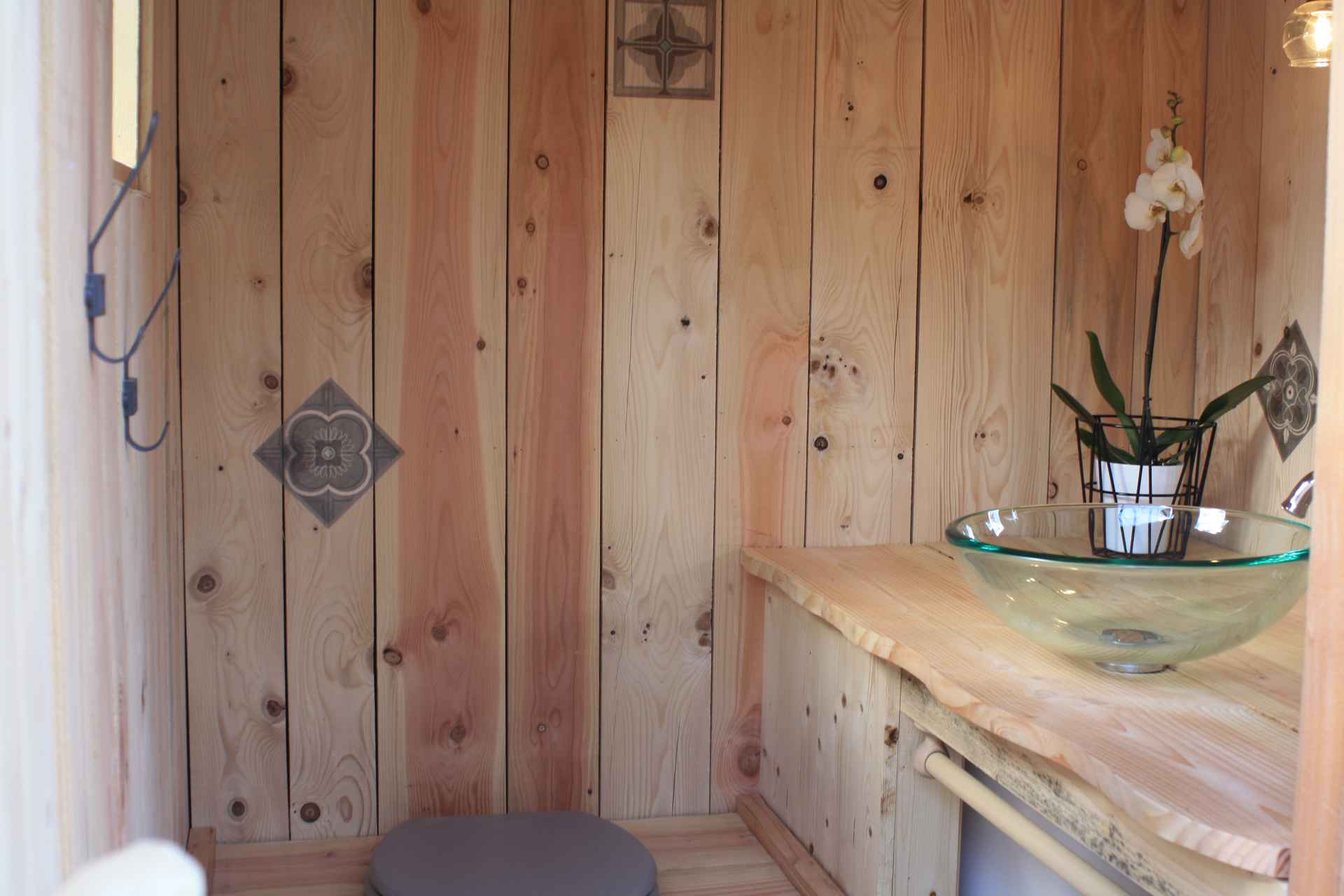IMG_7714 Hébergement insolite en bois en Auvergne-Rhône-Alpes, avec lavabo en verre et orchidée.