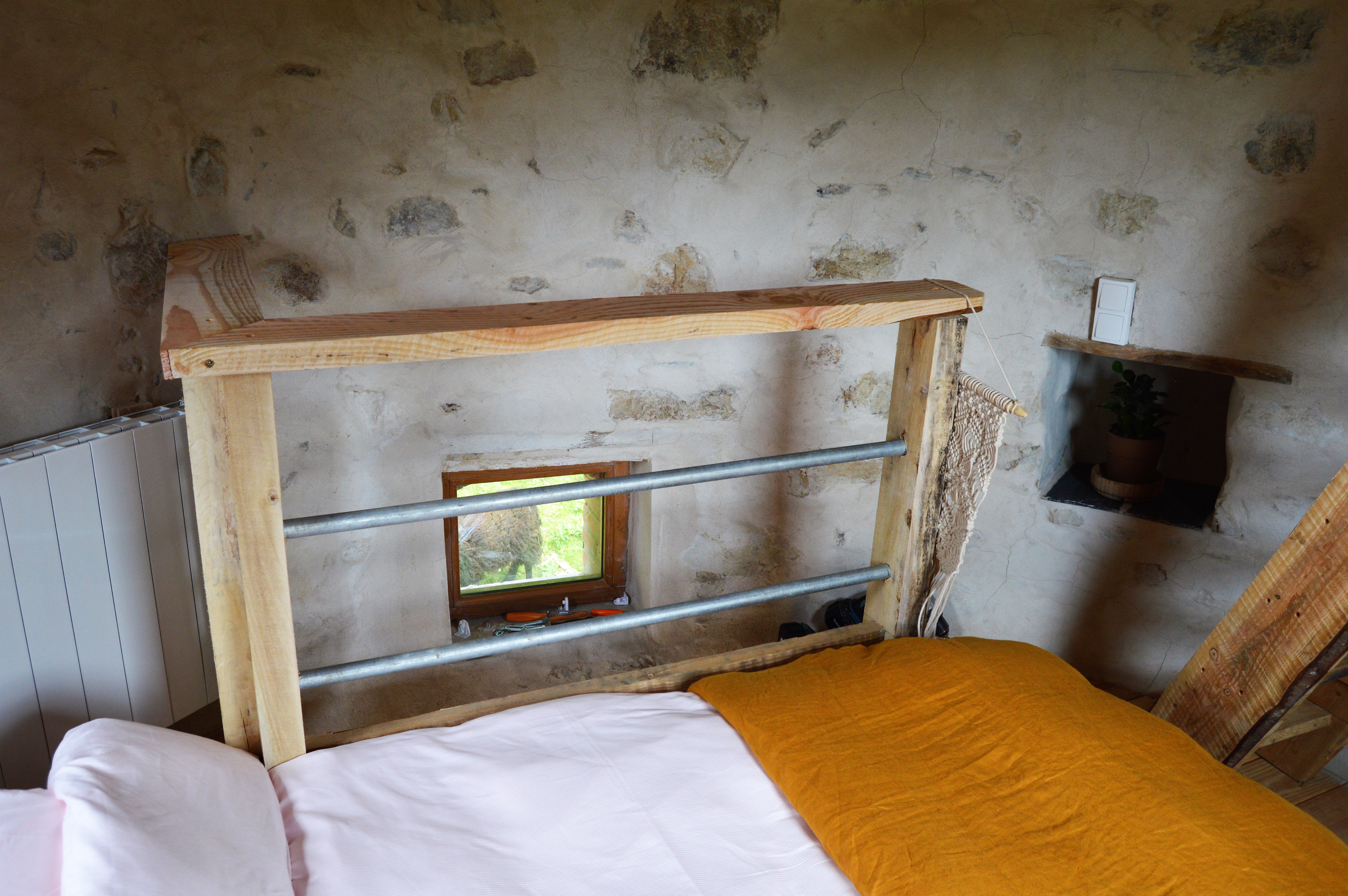DSC_0312 Chambre atypique en pierre avec lit en bois et fenêtre offrant une vue sur la nature.
