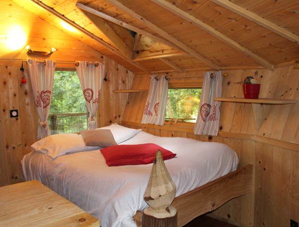 Chalet en bois chaleureux avec lit douillet et décor naturel en Bourgogne-Franche-Comté.