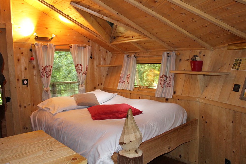Chalet en bois chaleureux avec lit douillet et décor naturel en Bourgogne-Franche-Comté.