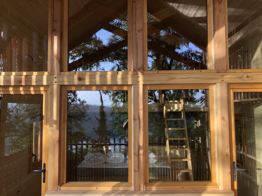 Cabane en bois avec grandes fenêtres, offrant une vue sur la nature environnante.