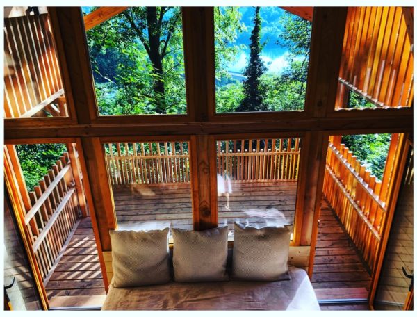 Cabane en bois avec vue sur la nature, balcon en bois et lumière naturelle.