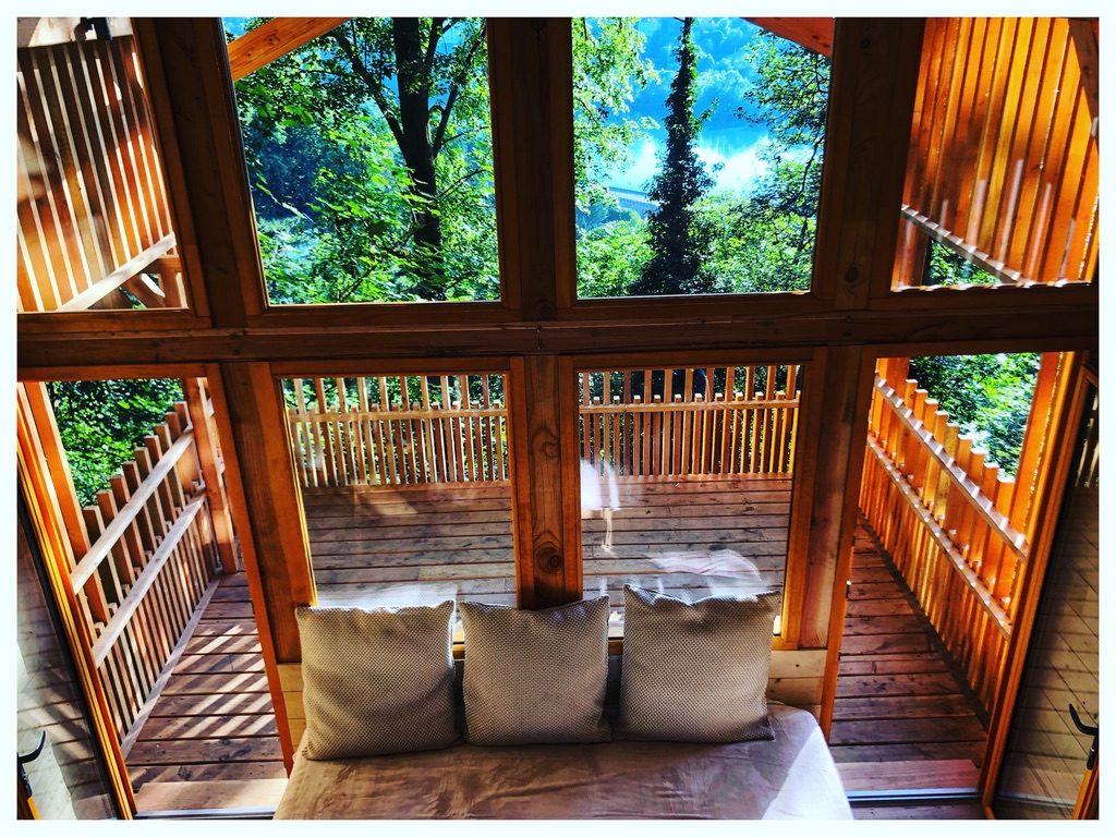 Cabane en bois avec vue sur la nature, balcon en bois et lumière naturelle.