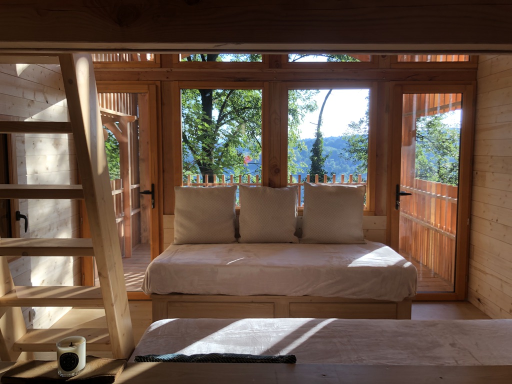 Cabane en bois avec grandes fenêtres offrant une vue sur la nature environnante.