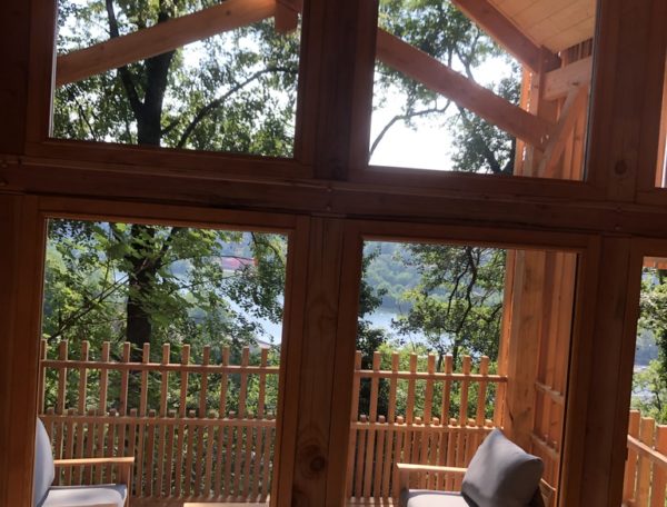 Cabane en bois avec vue sur le lac, entourée de verdure et de lumière naturelle.