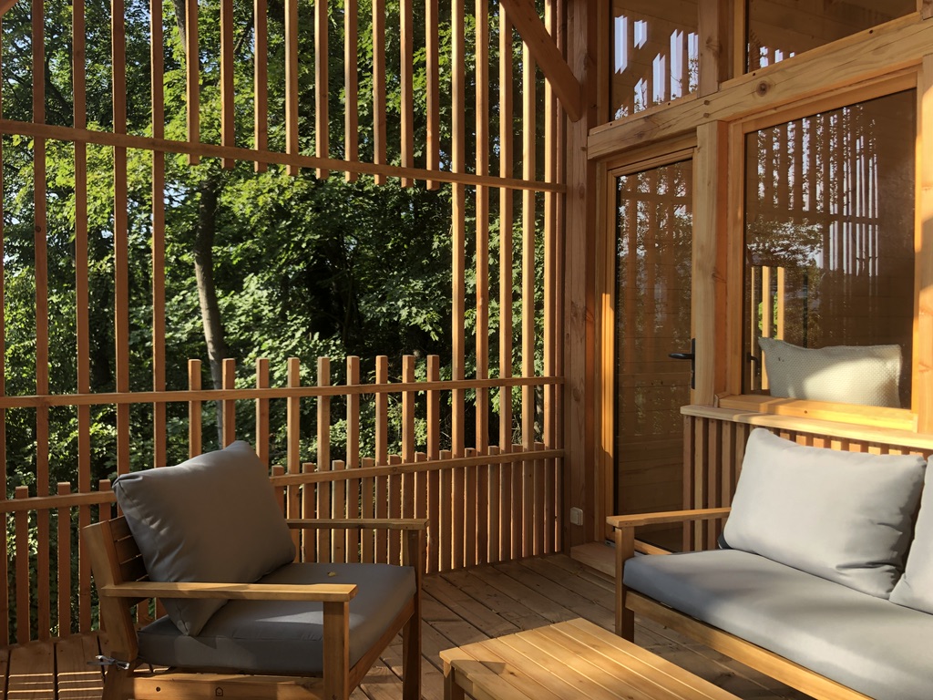 Cabane en bois avec terrasse, offrant une vue imprenable sur la forêt verdoyante.