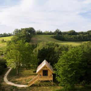 Cabane en bois perchée, entourée de verdure et de collines à Midi-Pyrénées.