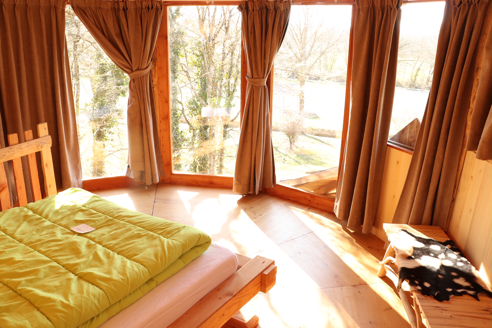 image1 (7) Cabane en bois avec grandes fenêtres et lit douillet, vue sur la nature.
