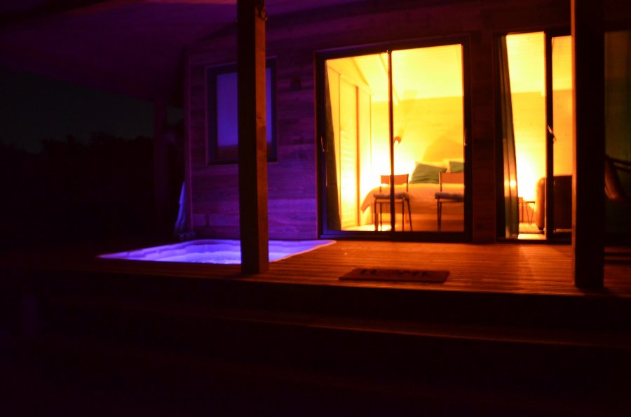 24686-fo-normal___v_02522e5f2a2084c24d56805d38b61fa1 Cabane insolite avec jacuzzi, éclairage chaleureux et ambiance nocturne apaisante.