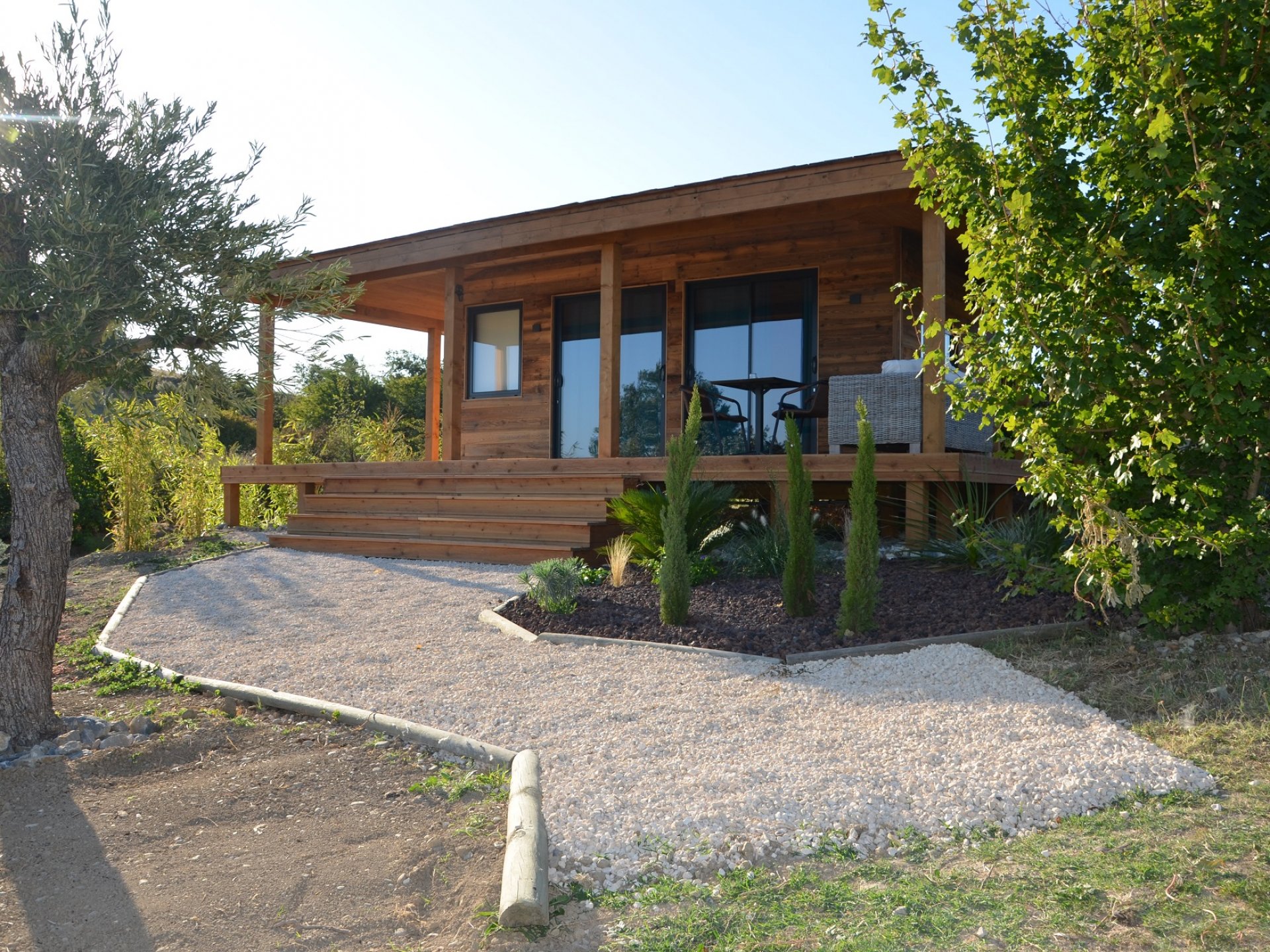 24690-fo-une___v_54752ba98815e473cee6c42c698b2e96 Chalet en bois avec terrasse, entouré de verdure à Languedoc-Roussillon.
