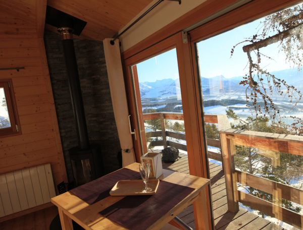 Cabane en bois avec vue panoramique sur les montagnes et un coin repas cosy.