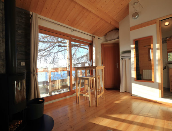 Cabane en bois lumineuse avec vue sur le lac et poêle à bois chaleureux.