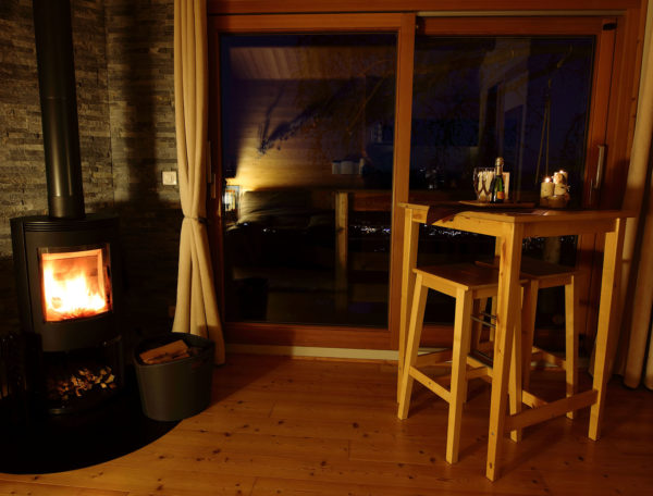 Hébergement insolite en bois avec poêle à bois, vue nocturne sur la vallée.