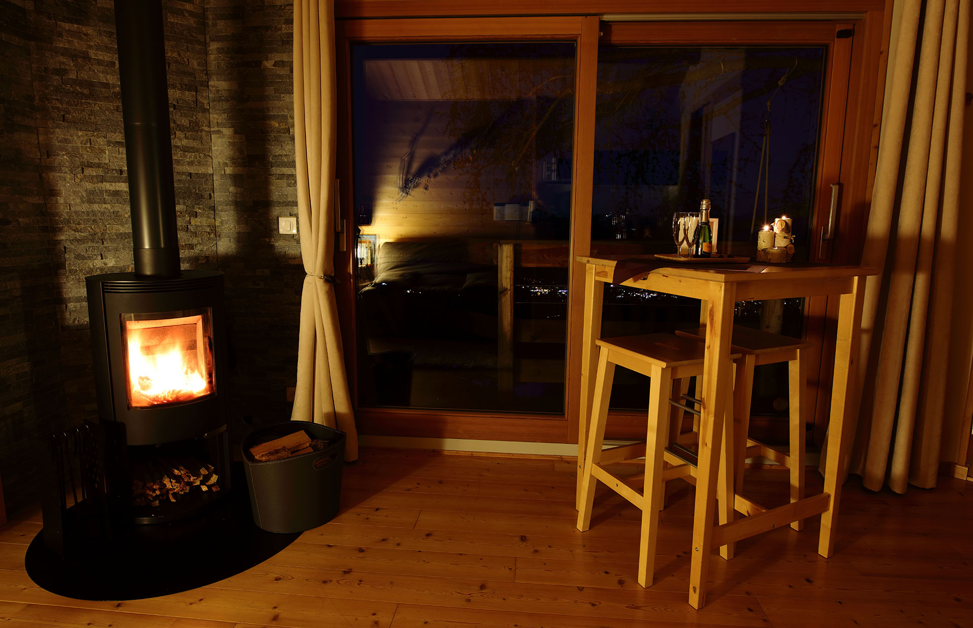 Hébergement insolite en bois avec poêle à bois, vue nocturne sur la vallée.
