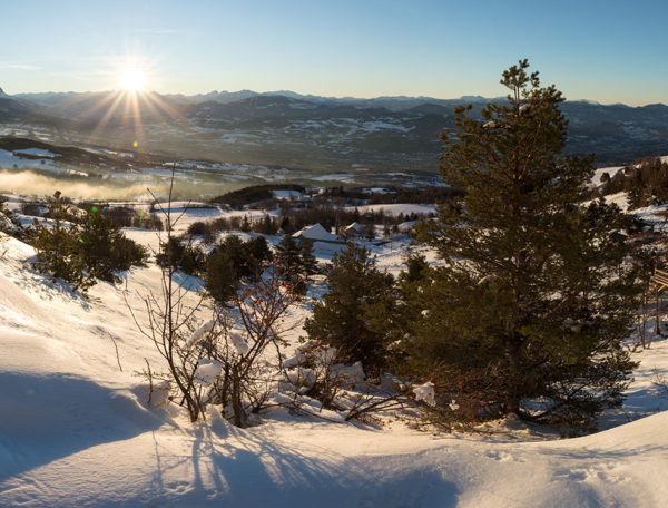 Cabane en bois perchée, vue panoramique sur les montagnes enneigées au coucher du soleil.