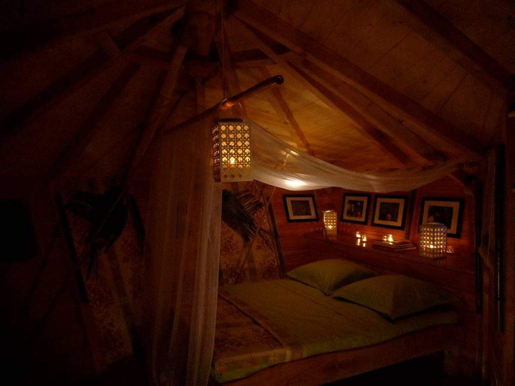 Cabane cosy avec lit douillet, éclairage chaleureux et décor en bois.