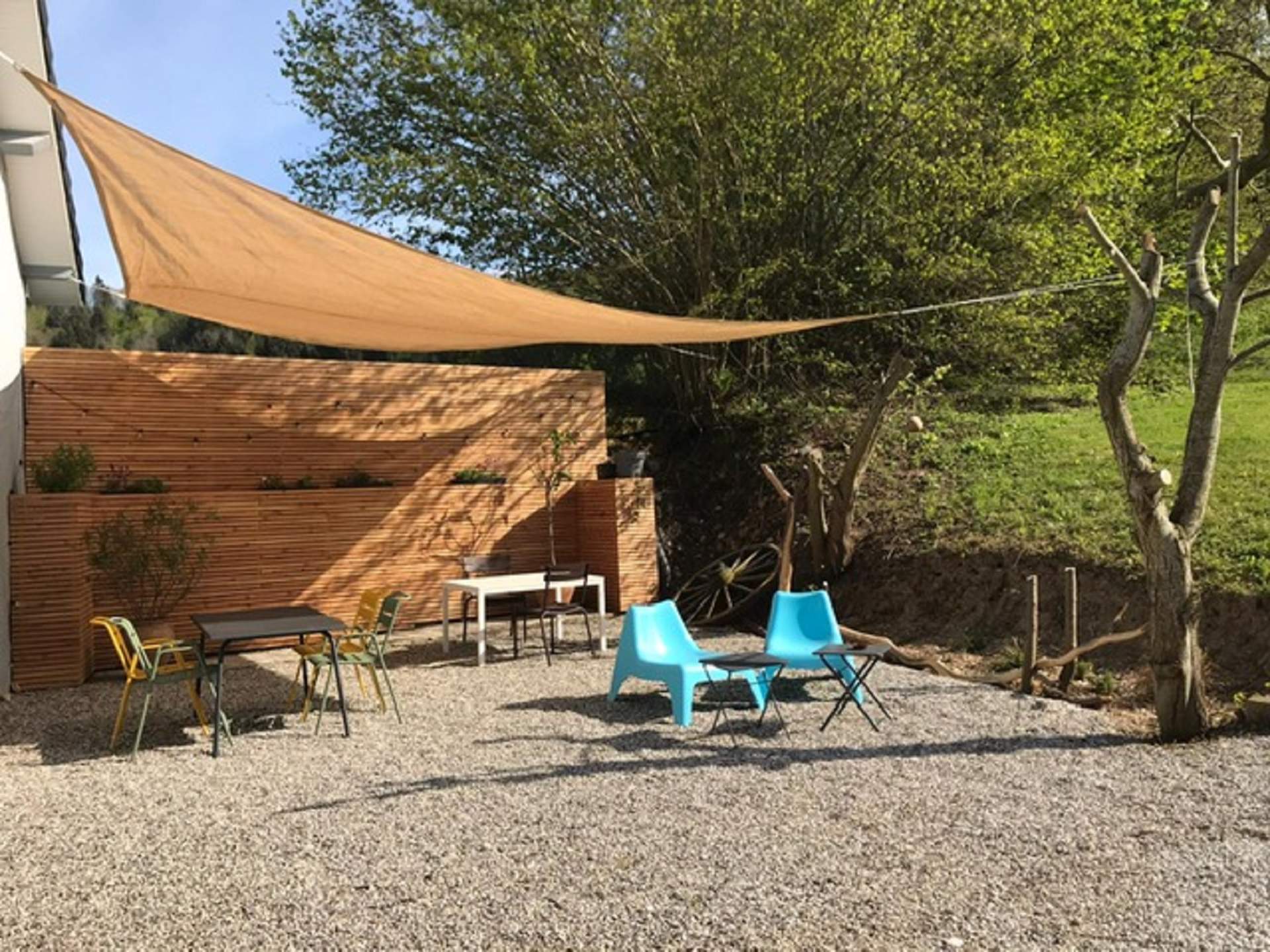 terrasse refuge Espace extérieur dun hébergement insolite avec chaises colorées et toile dombrage.