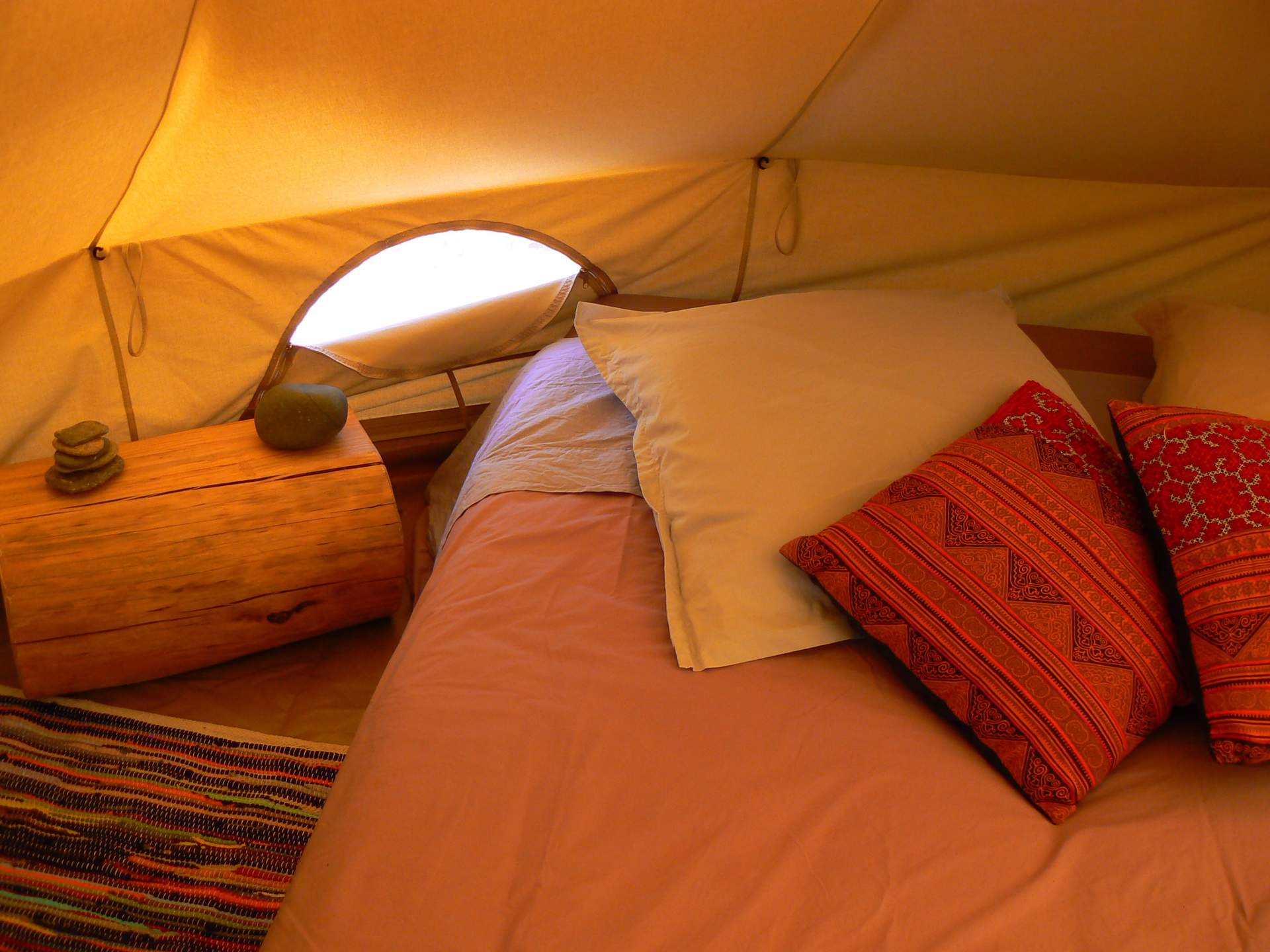 P1100048 Tente glamping cosy avec lit douillet et coussins colorés, au cœur du Languedoc-Roussillon.