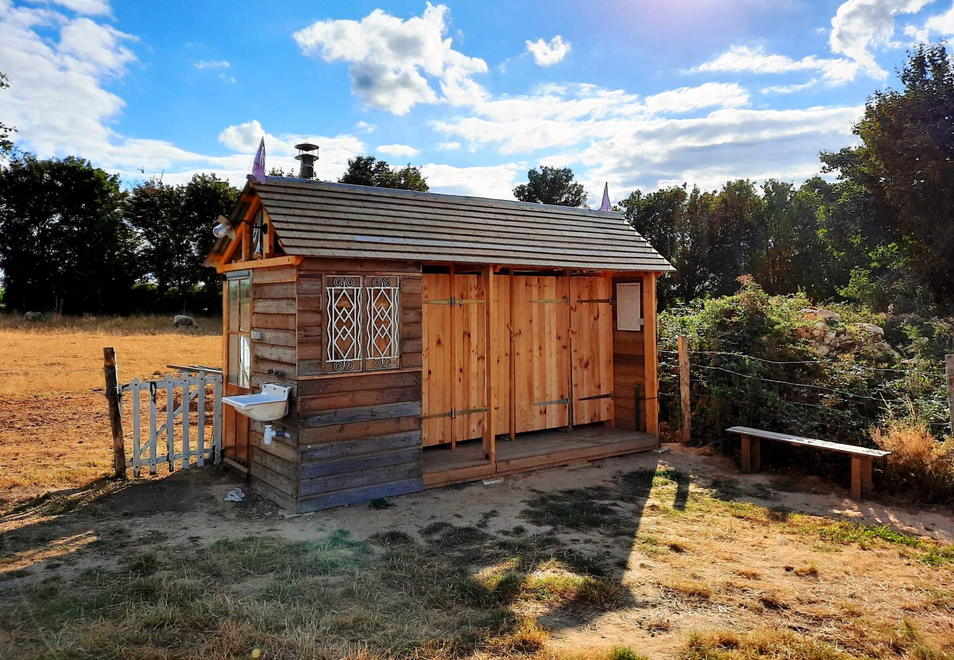 Boc sanitaire 1 Cabane en bois charmante, avec un toit en pente et un jardin verdoyant.