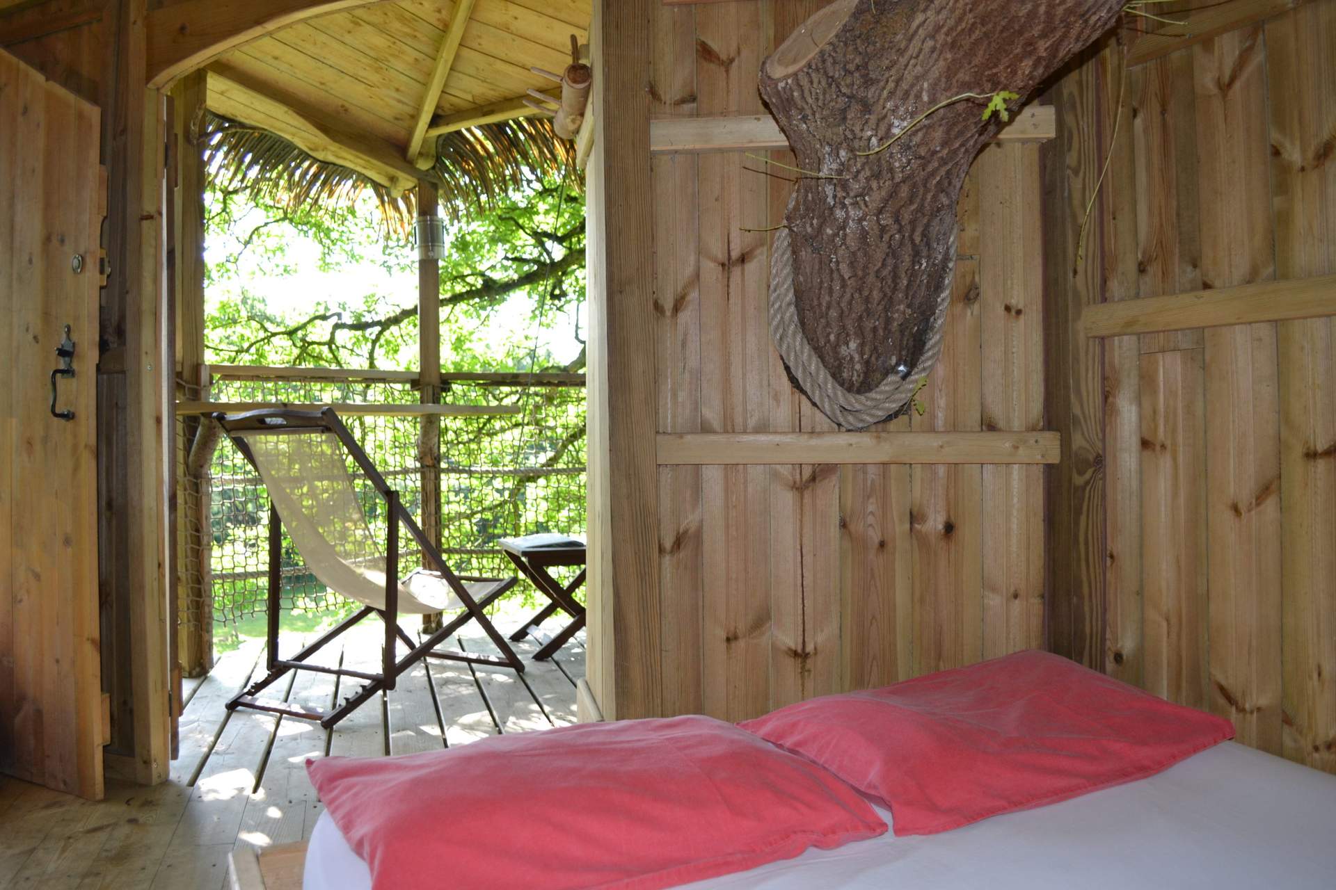 DSC_0720 Cabane perchée en bois avec vue sur la nature, lit confortable et décor chaleureux.