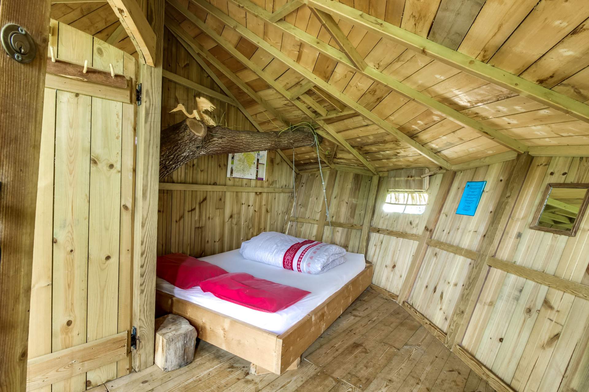 meero-1032 Cabane en bois avec un lit douillet et un arbre traversant le plafond.