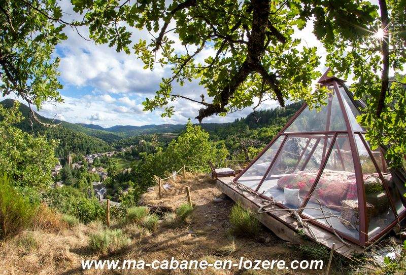 15RCABAN-1342-Modifier_resultat Cabane en verre sur pilotis, offrant une vue panoramique sur la vallée verdoyante.