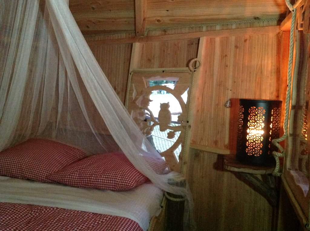 2014-07-09 20.05.24 Cabane en bois avec lit à baldaquin et lumière tamisée, ambiance chaleureuse.
